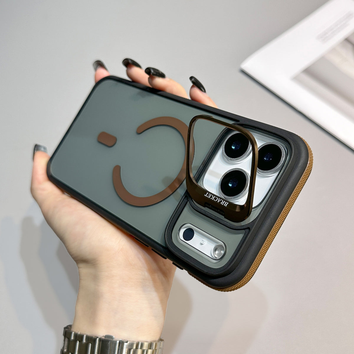 This iPhone case features a frosted, semi-translucent back panel highlighted by brown accents. A brown MagSafe-style magnetic ring with a small accent bar sits near the center, creating a smiley face shape.