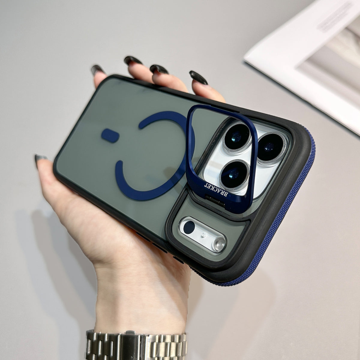 This iPhone case features a frosted, semi-translucent back panel highlighted by dark blue accents. A dark blue MagSafe-style magnetic ring with a small accent bar sits near the center.
